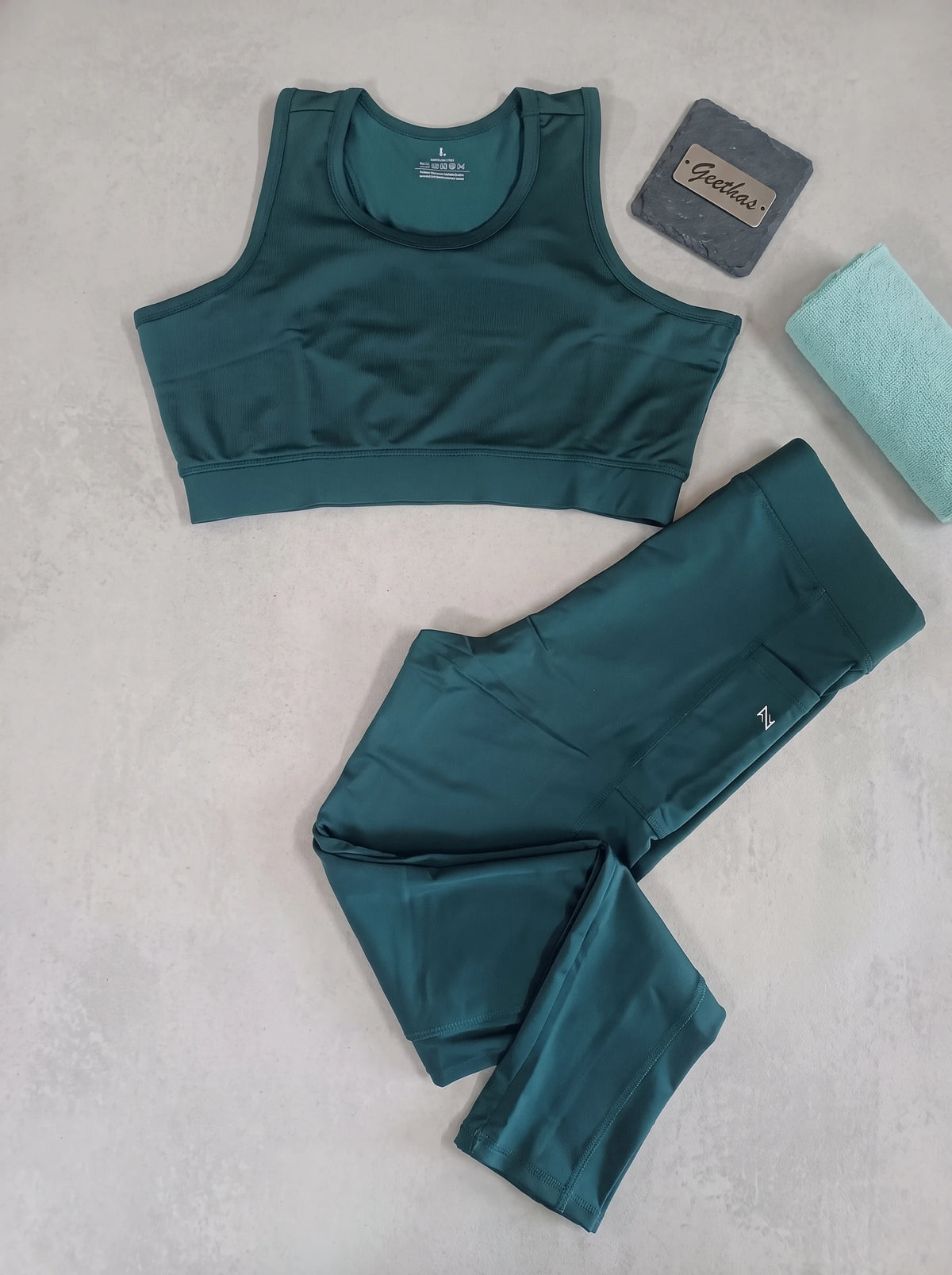 Teal blue sleeveless activewear top and high-waisted leggings set displayed flat