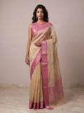 Model wearing a light gold kota tissue saree with pink zari border and embroidered leaf motifs