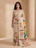 Model wearing beige ready-to-wear linen saree with colourful bird and branch print and tasselled pallu