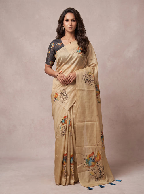 Model wearing a beige linen floral printed saree with blue tassels at the pallu