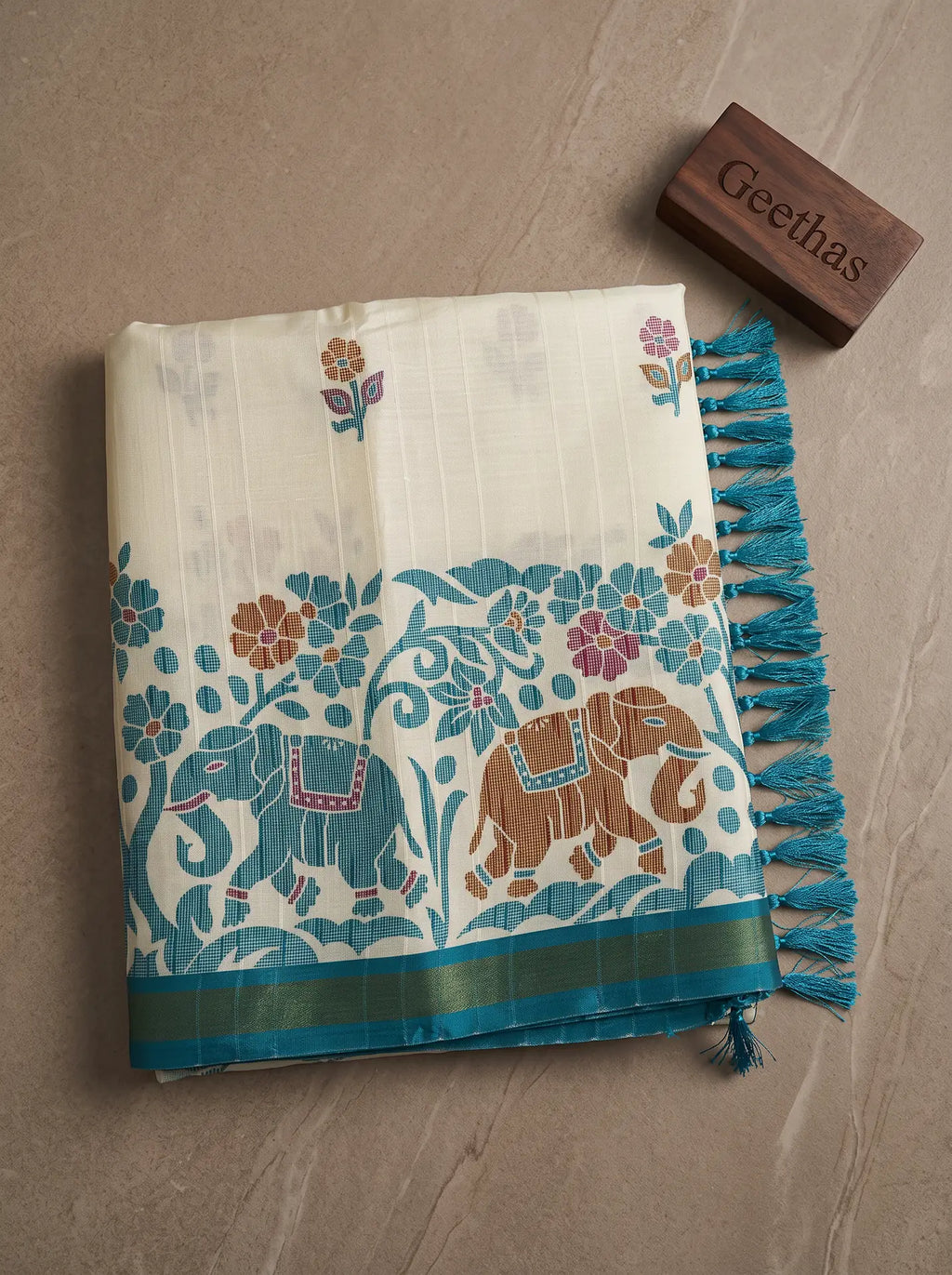 Folded ivory white slub linen saree with teal floral and elephant print, teal border and tasselled pallu