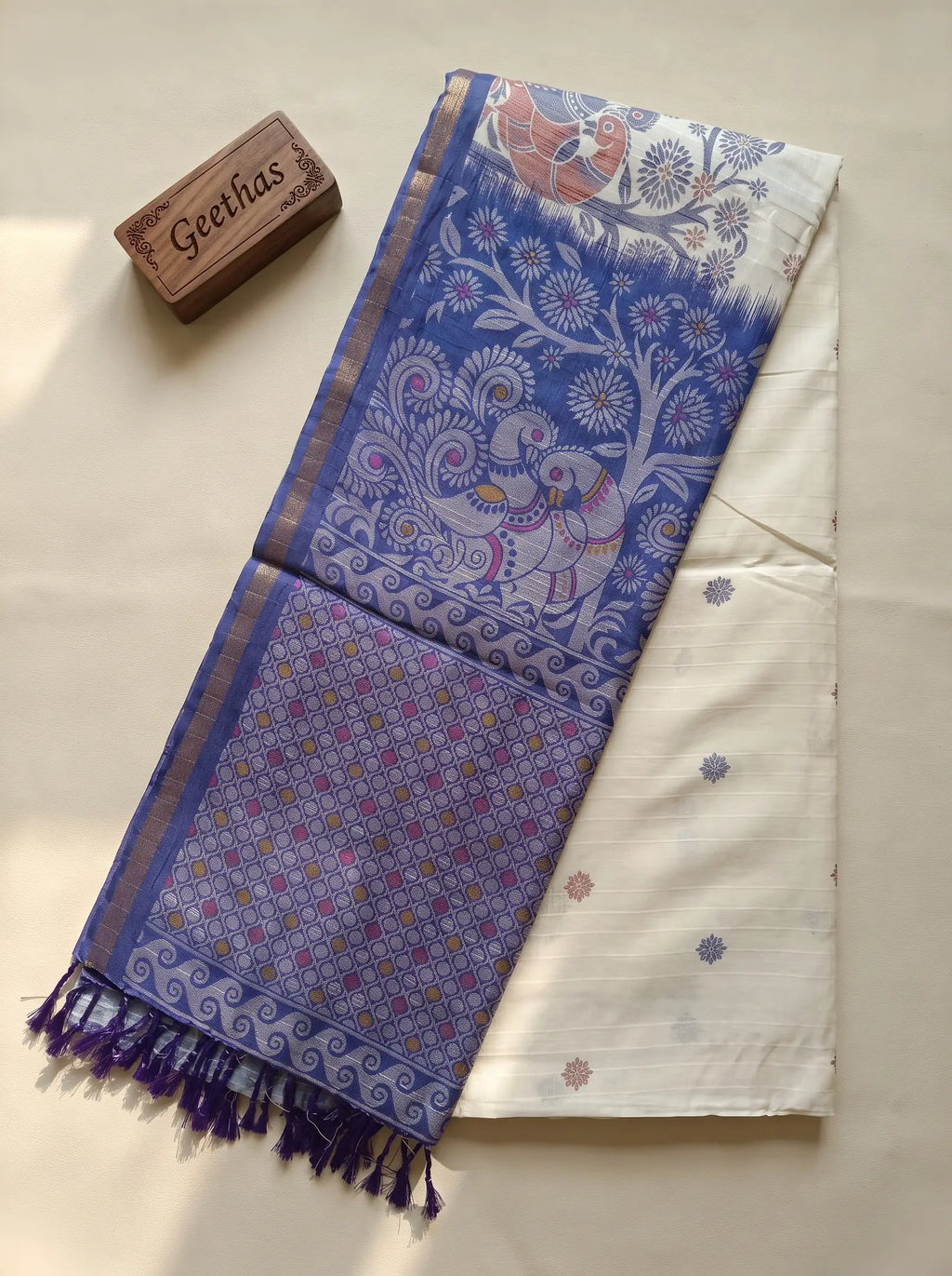White slub linen saree with violet printed pallu, patterned border and tasselled end displayed flat