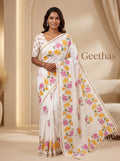 Model wearing a white slub linen saree with pink and yellow floral print, subtle beige-gold toned border and tasselled pallu
