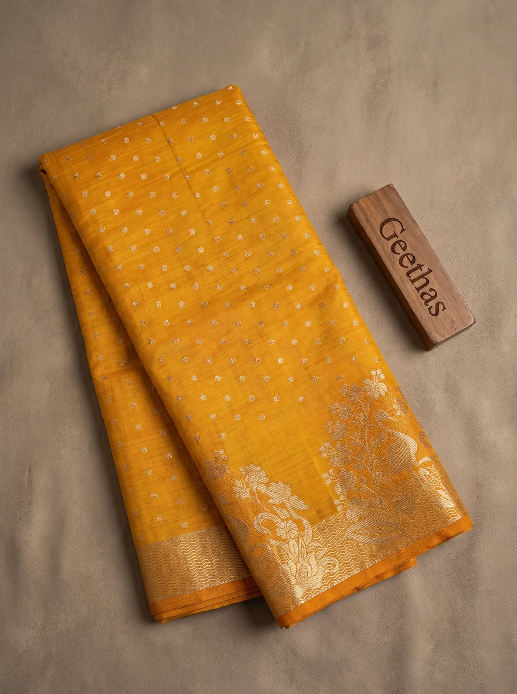 Folded golden yellow semi tussar silk saree with zari butti motifs and floral zari border