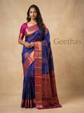 Model wearing a royal blue semi silk saree with copper-toned woven motifs and magenta pallu border