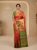 Model wearing vermilion orange ready-to-wear semi silk saree with woven motifs, gold-toned border and green edging