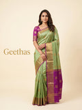 Model wearing pista green semi silk saree with gold-toned woven motifs, paisley border and magenta edging