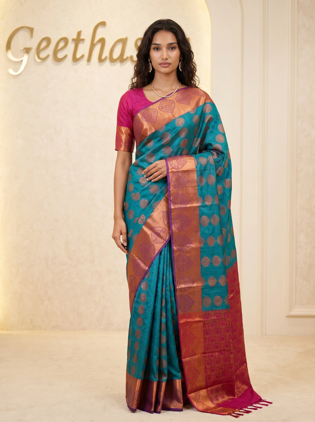 Model wearing a teal blue semi silk saree with woven motifs, copper-toned border and magenta pallu