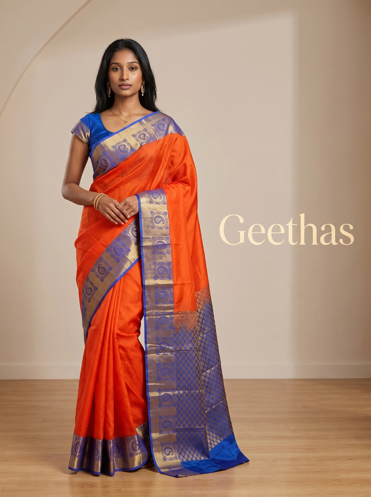 Model wearing an orange semi silk saree with royal blue and antique gold paisley woven border