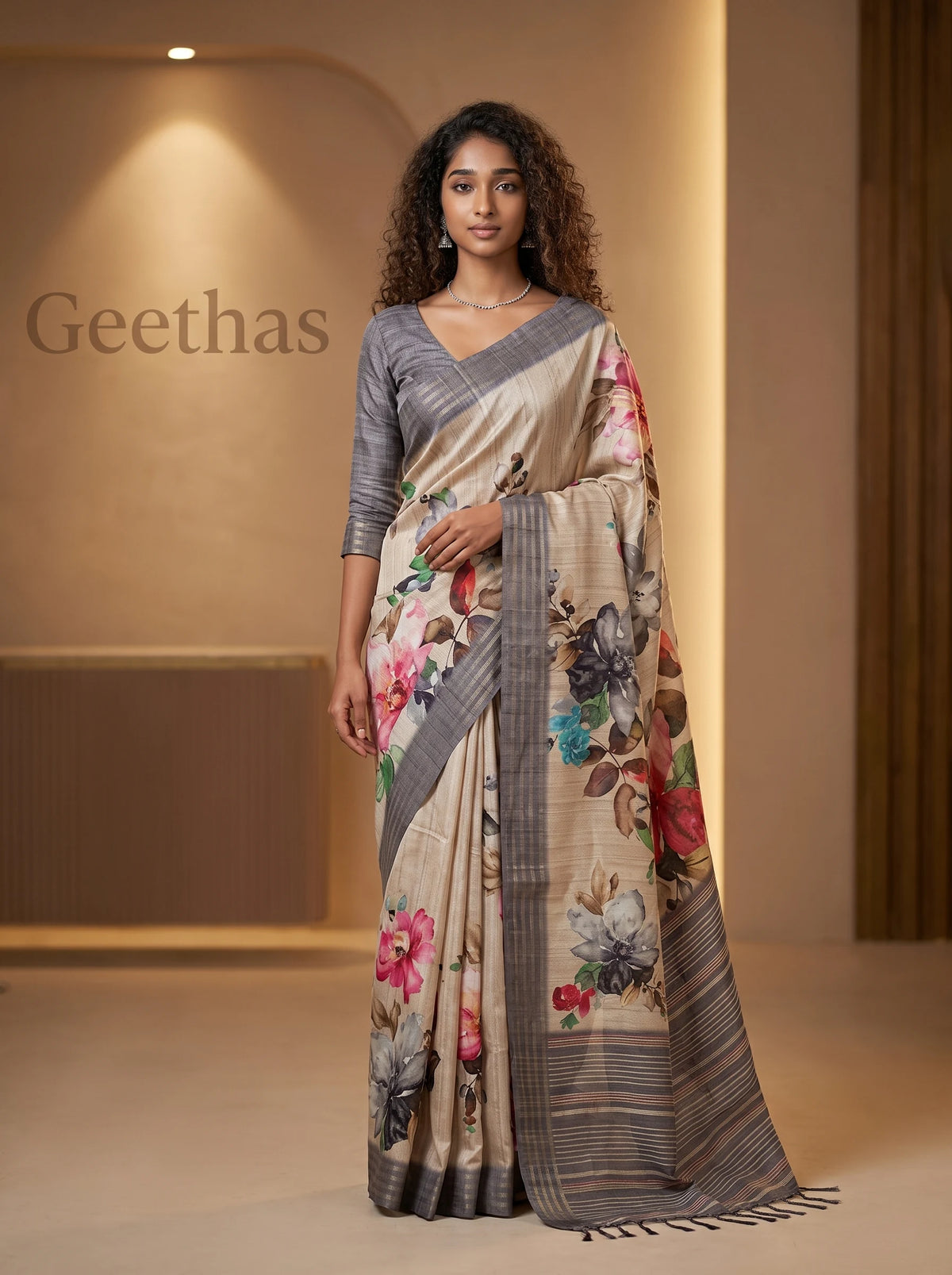 Model wearing a beige semi tussar saree with multicolour floral prints and a grey striped border