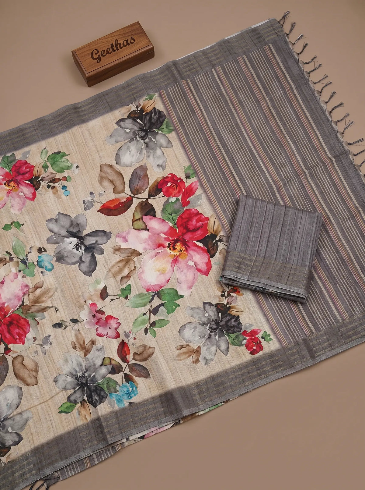 Beige floral printed semi tussar saree displayed flat with grey striped pallu and unstitched blouse piece