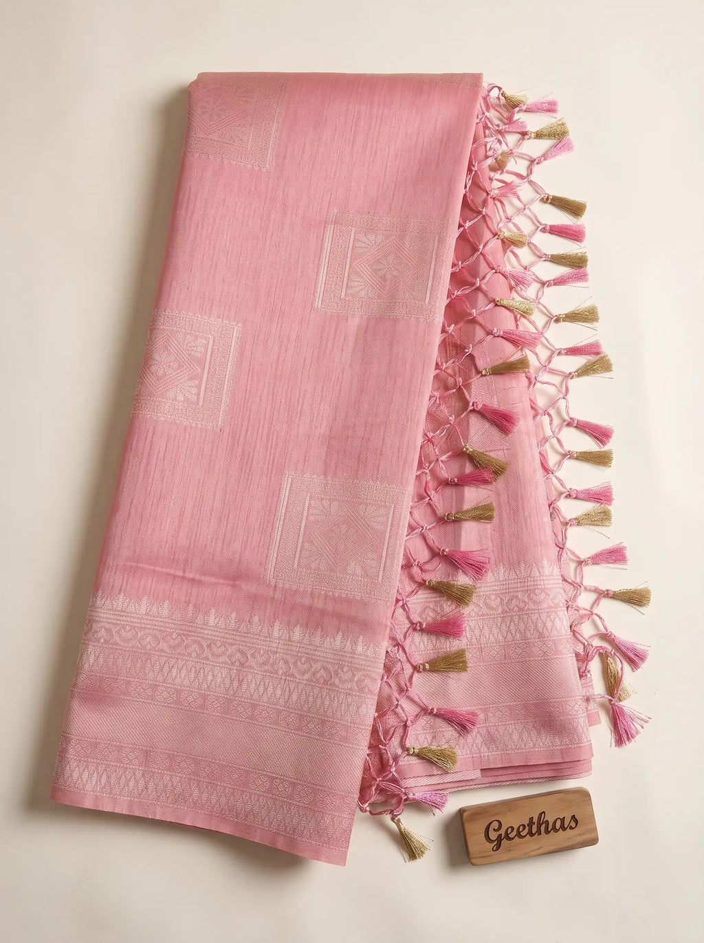 Pastel pink soft tissue woven saree with patterned border and pink and gold-toned tassled pallu