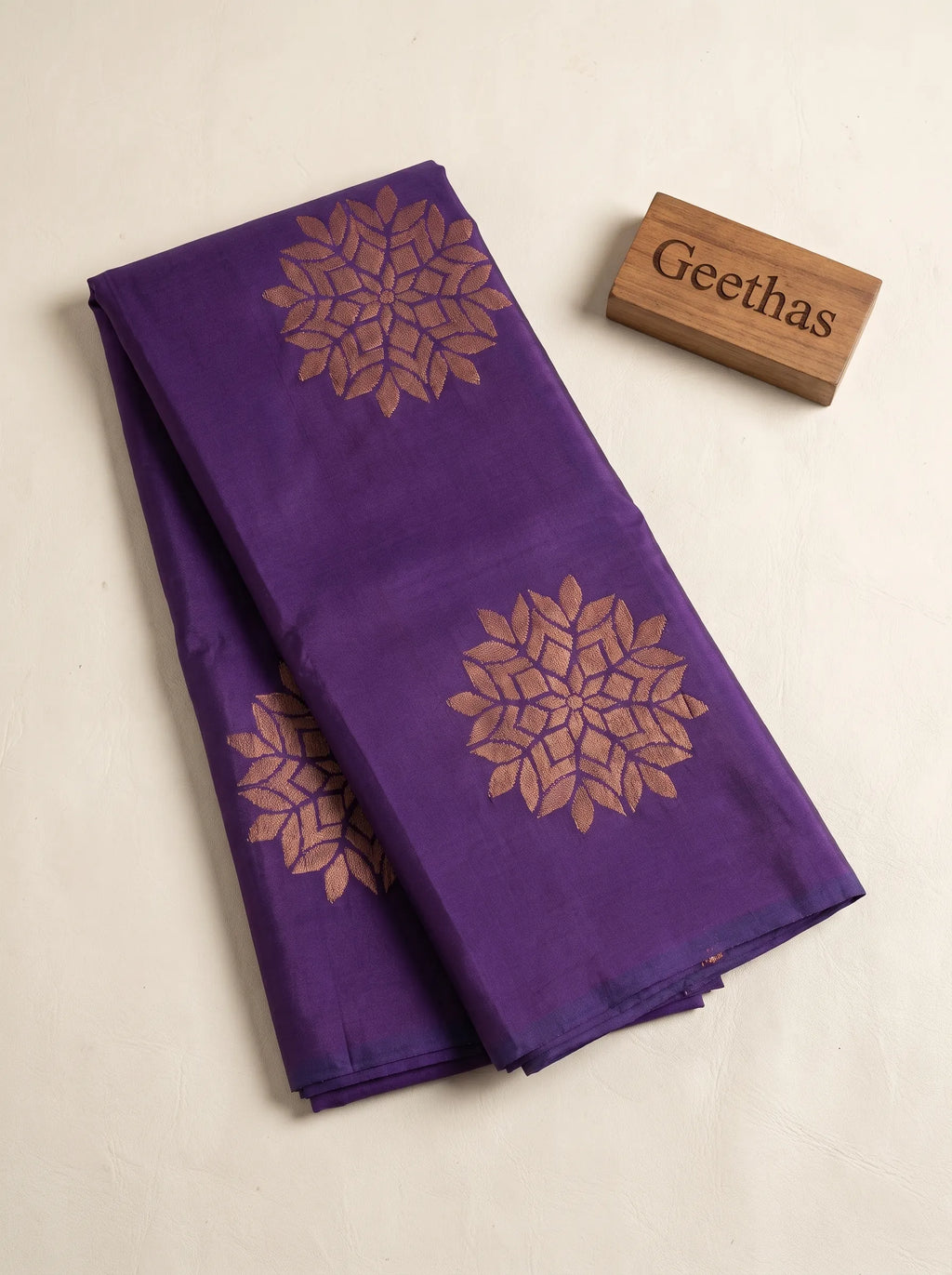 Folded violet soft silk saree with muted gold woven floral motifs