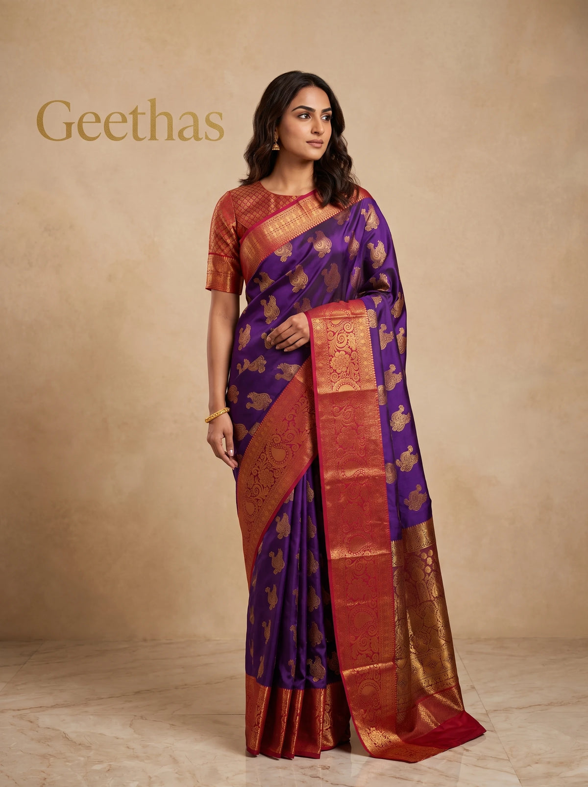 Model wearing violet soft silk saree with gold-toned paisley motifs and deep red woven border