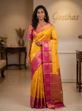 Model wearing mustard yellow soft silk saree with gold-toned motifs, magenta border and detailed pallu