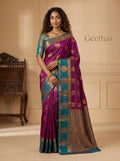 Model wearing a magenta pink soft silk saree with gold-toned woven motifs, teal border and ornate pallu