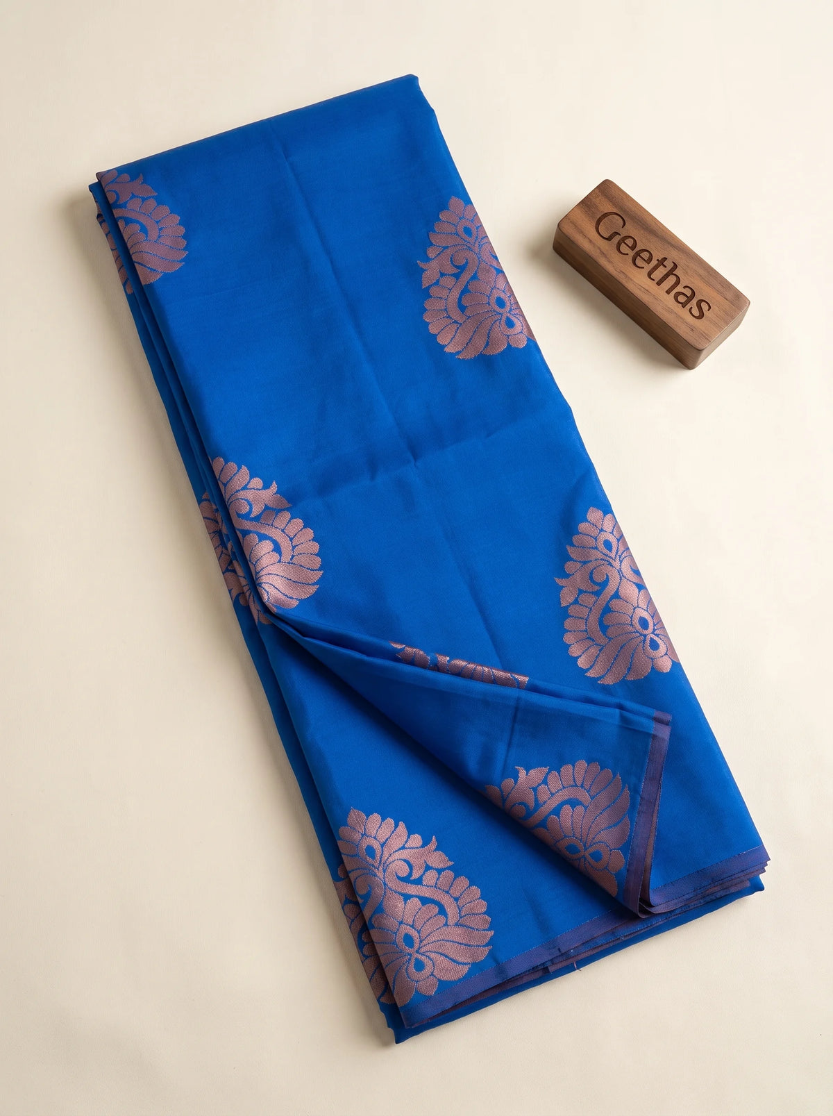 Royal blue soft silk saree displayed folded, showing mauve floral woven motifs and plum border