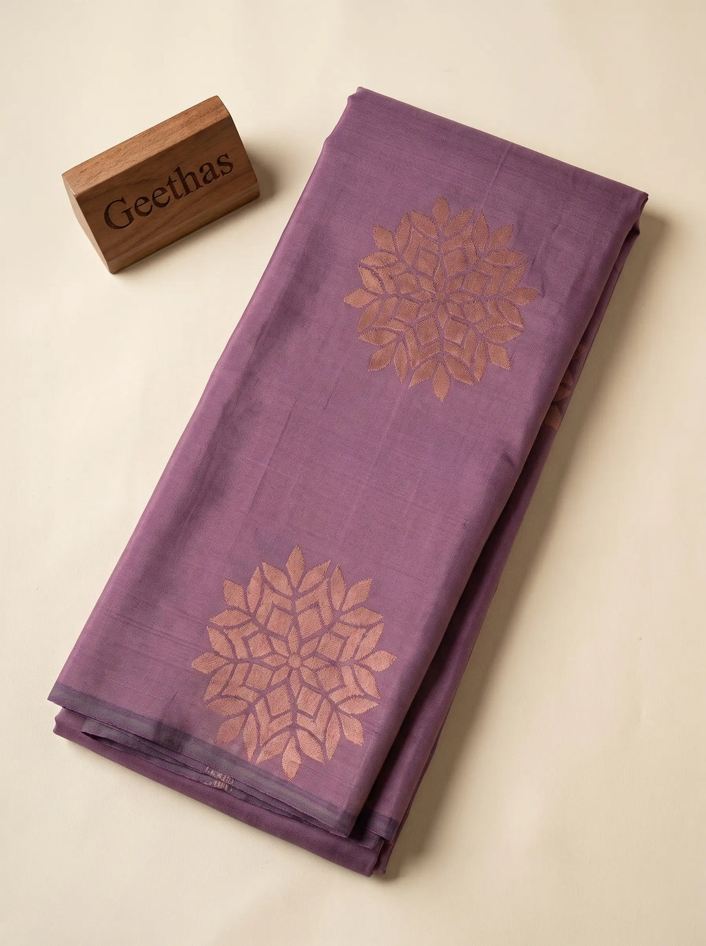Folded lavender soft silk saree with woven gold-tone floral-inspired motifs
