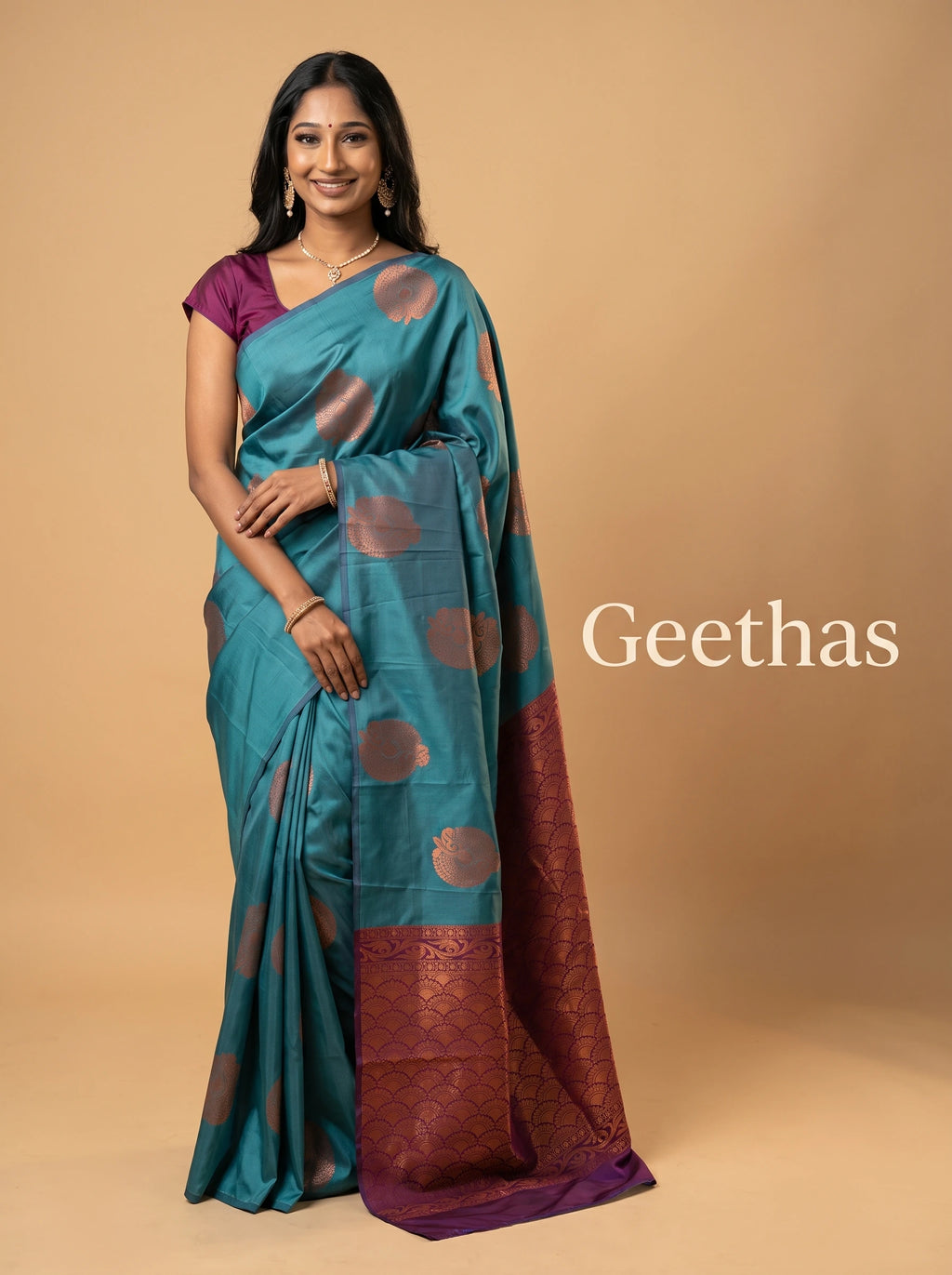 Model wearing a teal blue soft silk saree with copper-toned woven motifs and a deep purple patterned pallu