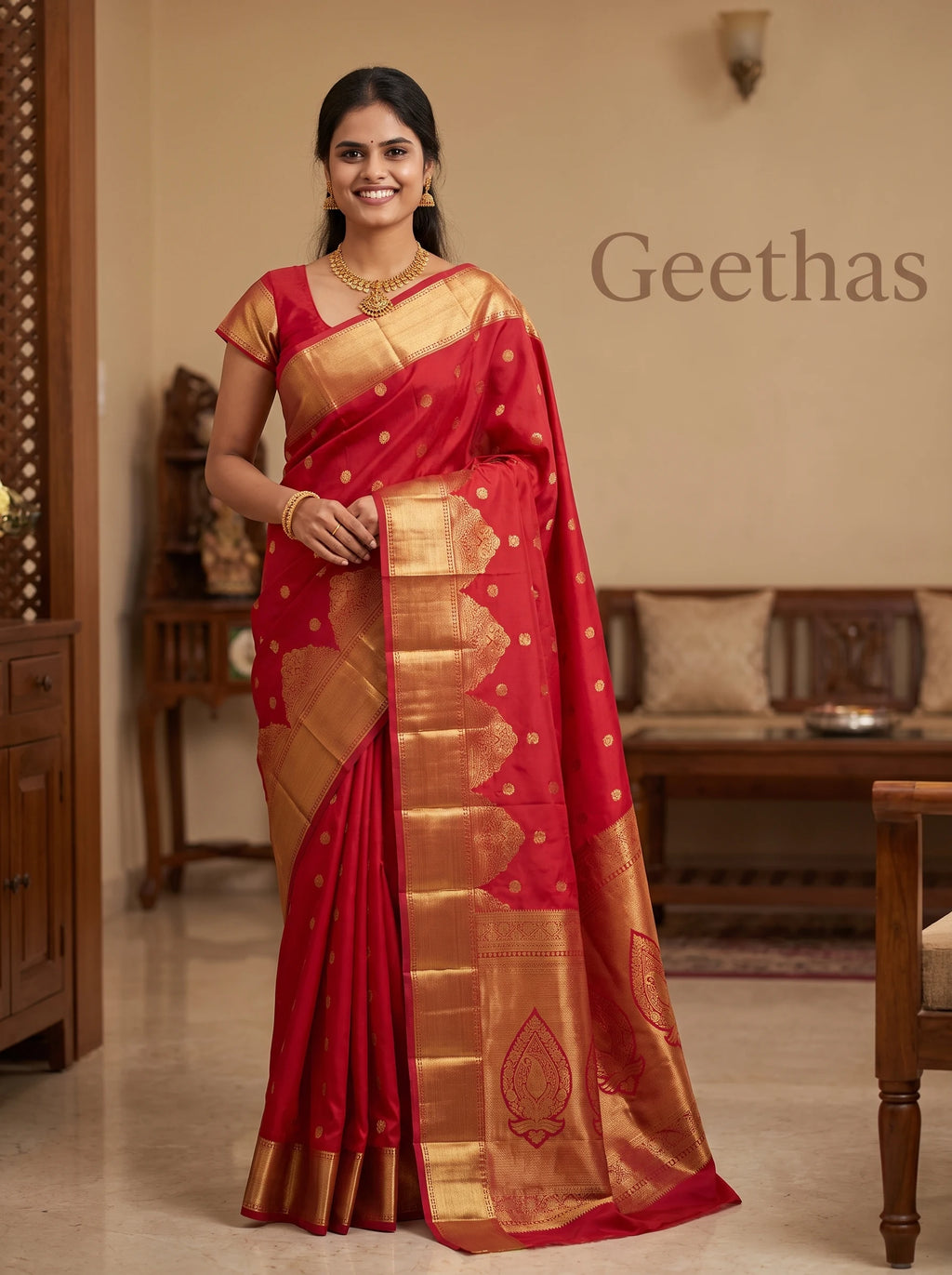 Model wearing a deep red soft silk saree with gold-toned woven motifs and ornate zari border