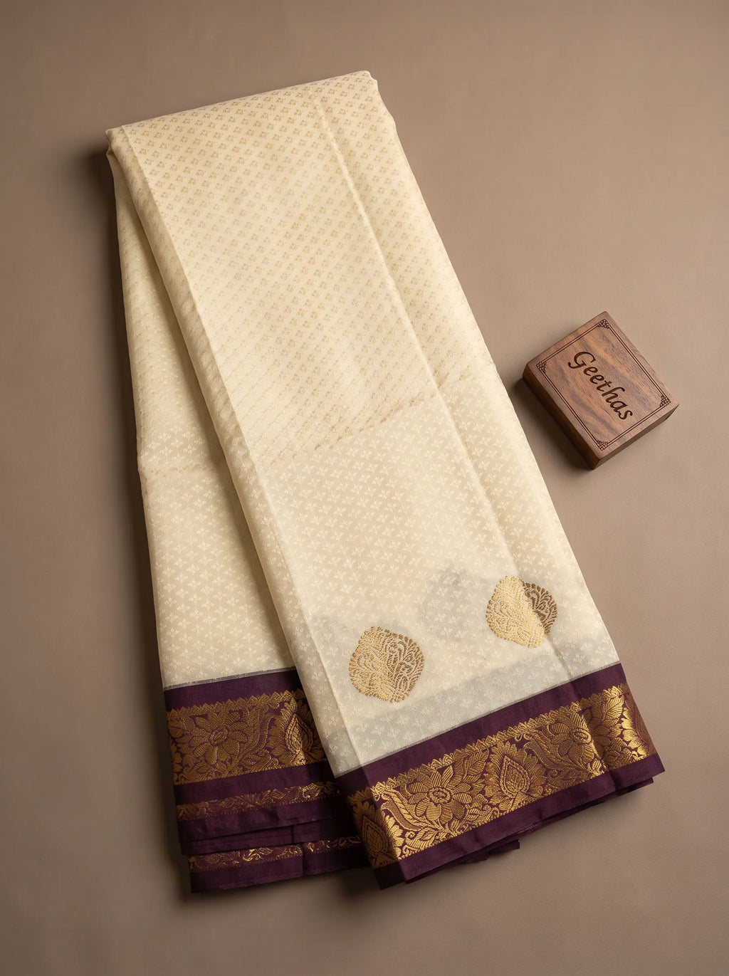 Half white soft silk saree displayed with woven motifs and deep brown gold-toned border