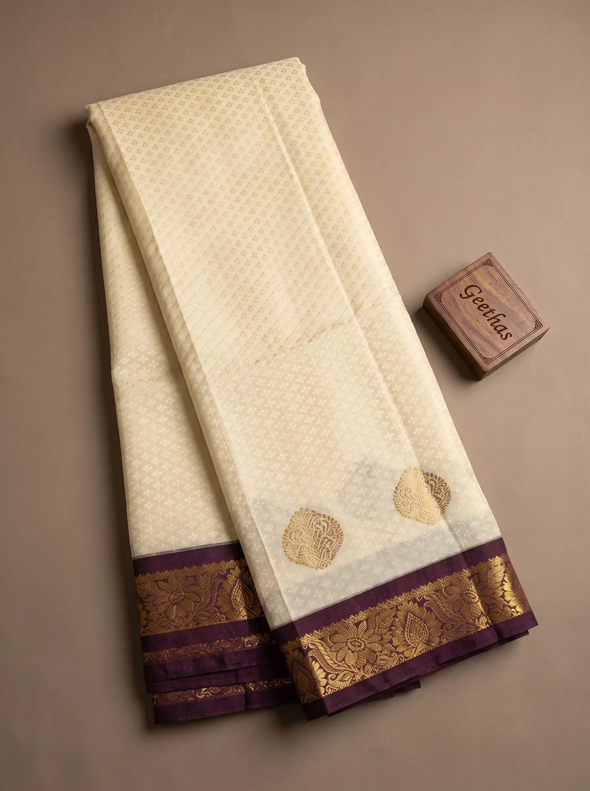 Half white soft silk saree displayed with woven motifs and deep brown gold-toned border