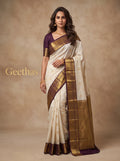 Model wearing a half white soft silk saree with gold-toned woven motifs and brown border