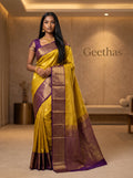 Model wearing a mustard yellow soft silk saree with a deep purple zari border and pallu.