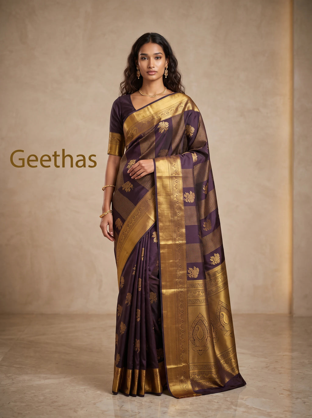 Model wearing a deep brown soft silk saree with gold-toned floral motifs and a broad decorative woven border