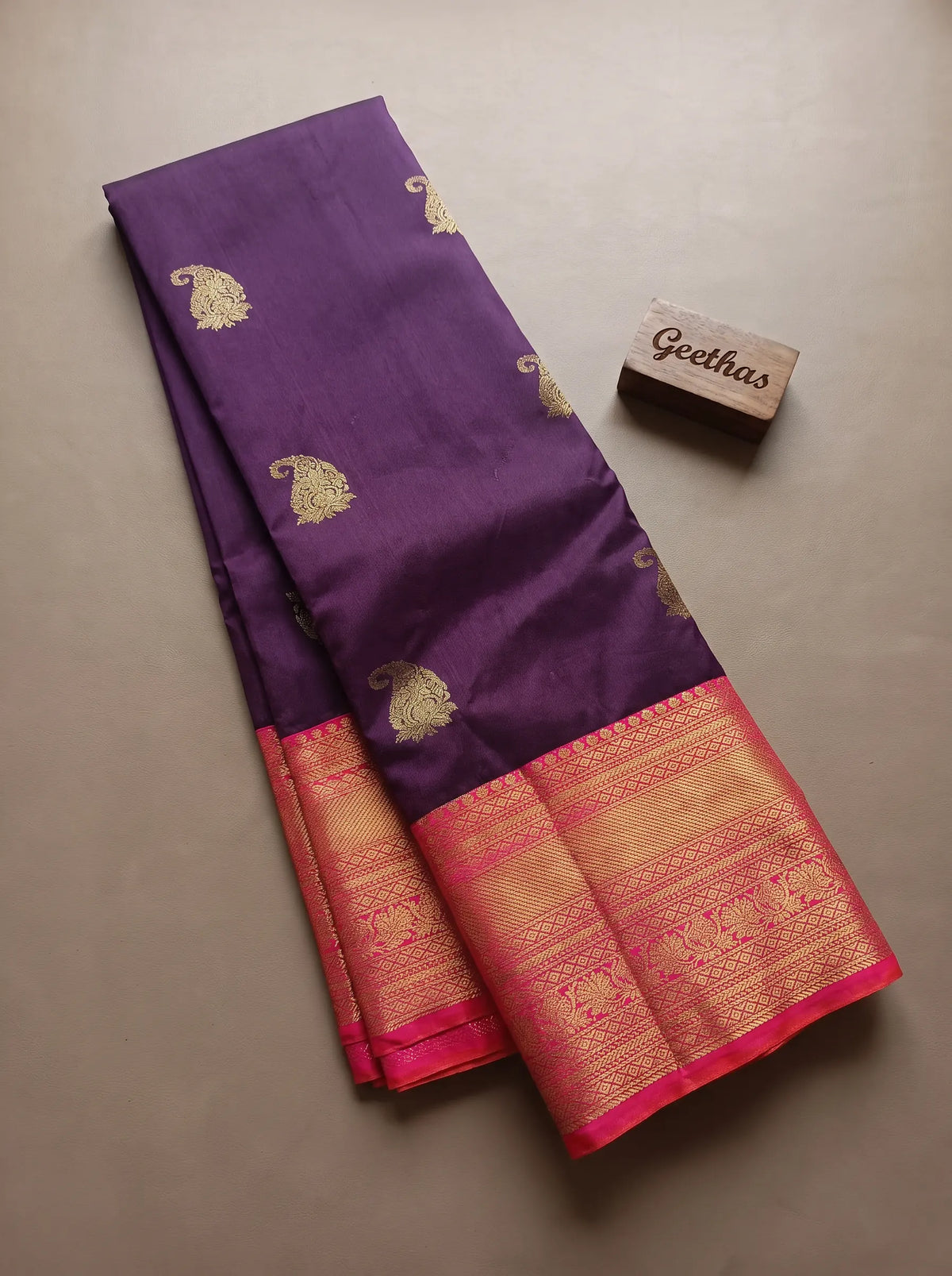 Violet soft silk saree with gold-toned paisley motifs and a coral red zari-woven border