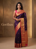 Model wearing a violet soft silk saree with gold-toned paisley motifs and coral red zari border