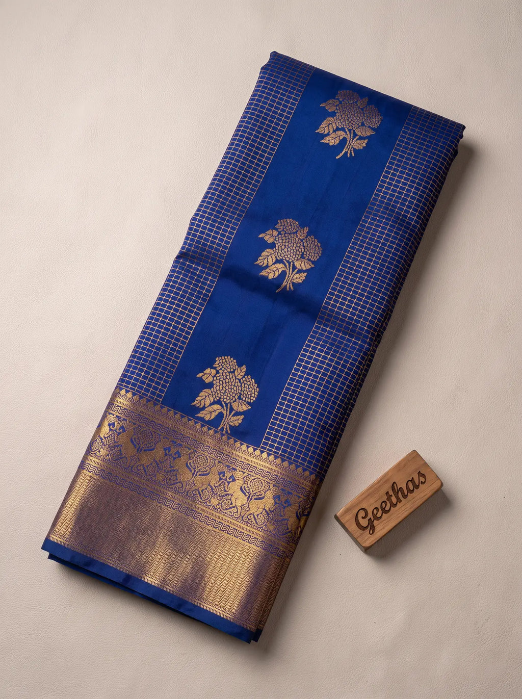 Royal blue soft silk saree with gold-tone woven floral motifs, check panels and ornate zari border