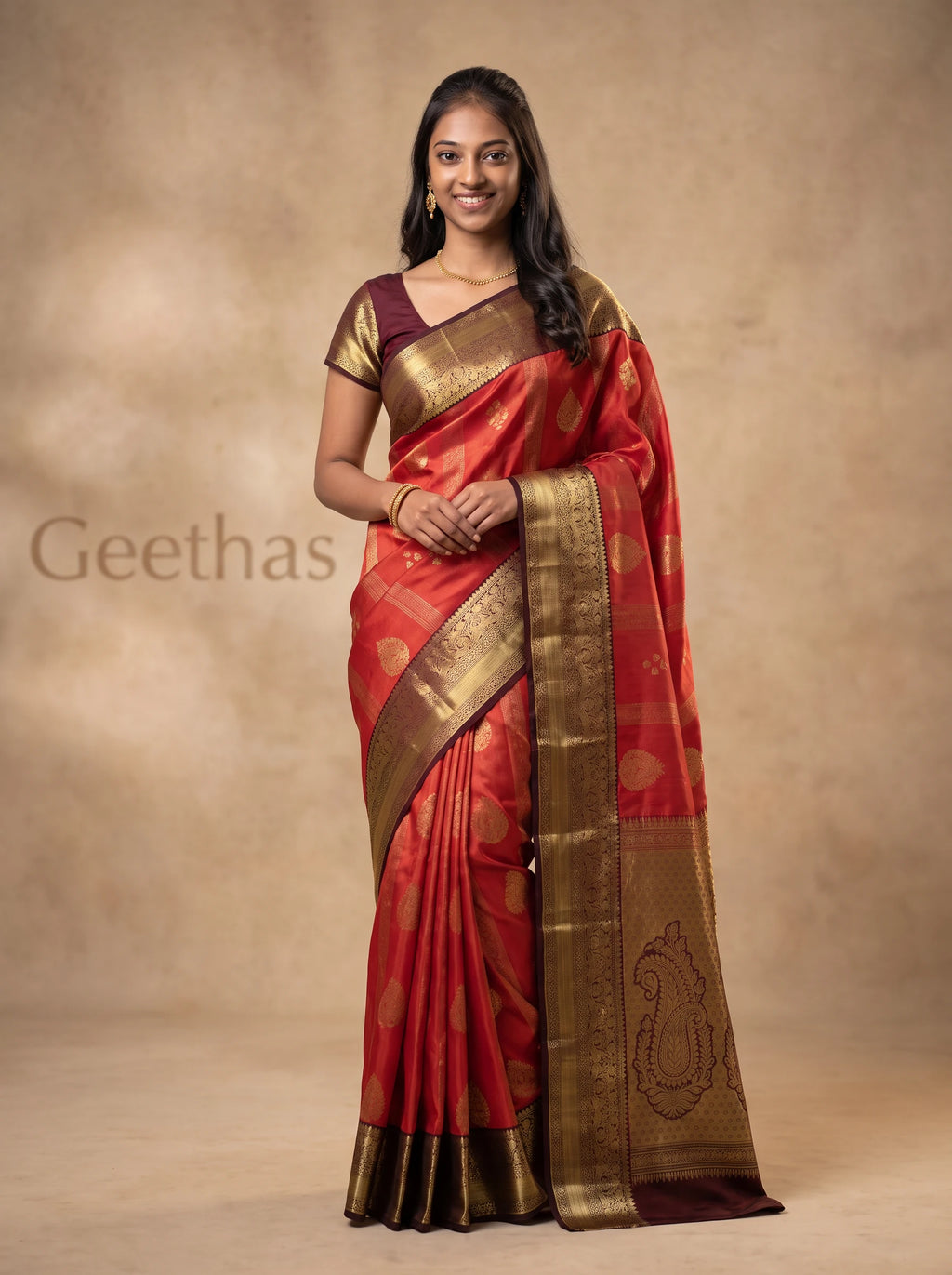 Model wearing a burnt orange soft silk saree with gold-toned zari paisley motifs and a wide ornate border