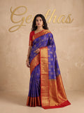 Model wearing a royal blue soft silk saree with gold-toned woven motifs and a wide red zari border.