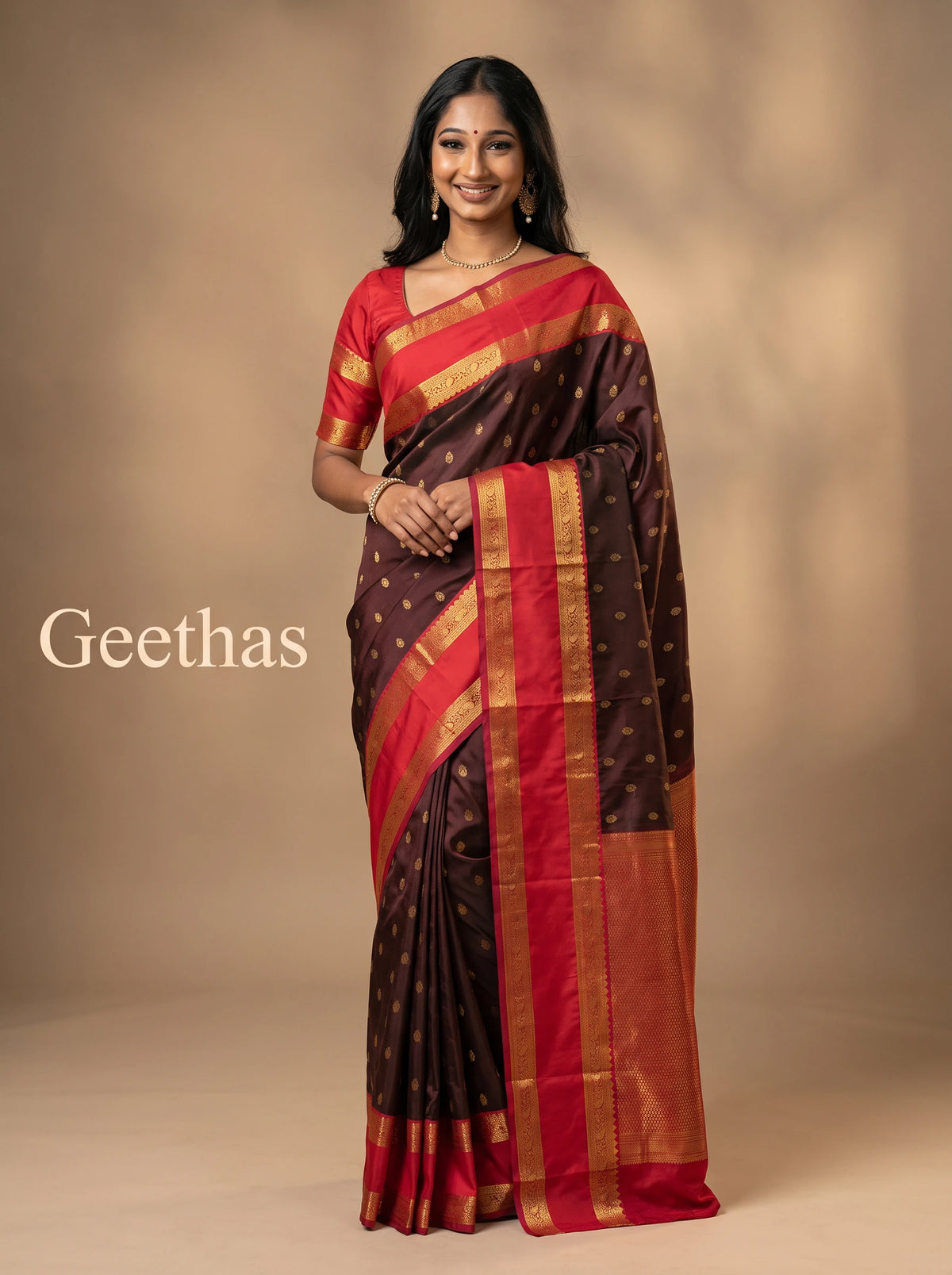 Model wearing a deep brown soft silk saree with gold-toned motifs, red pallu and decorative zari-style border