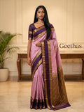 Model wearing an onion pink soft silk saree with a contrasting purple zari border and pallu