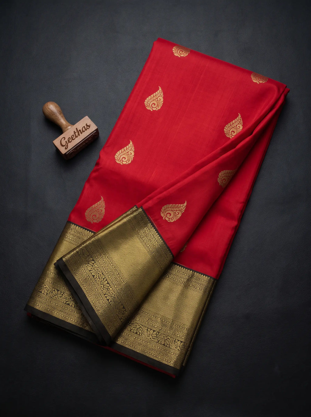 Pinkish red soft silk saree with gold-tone paisley motifs and broad woven zari border