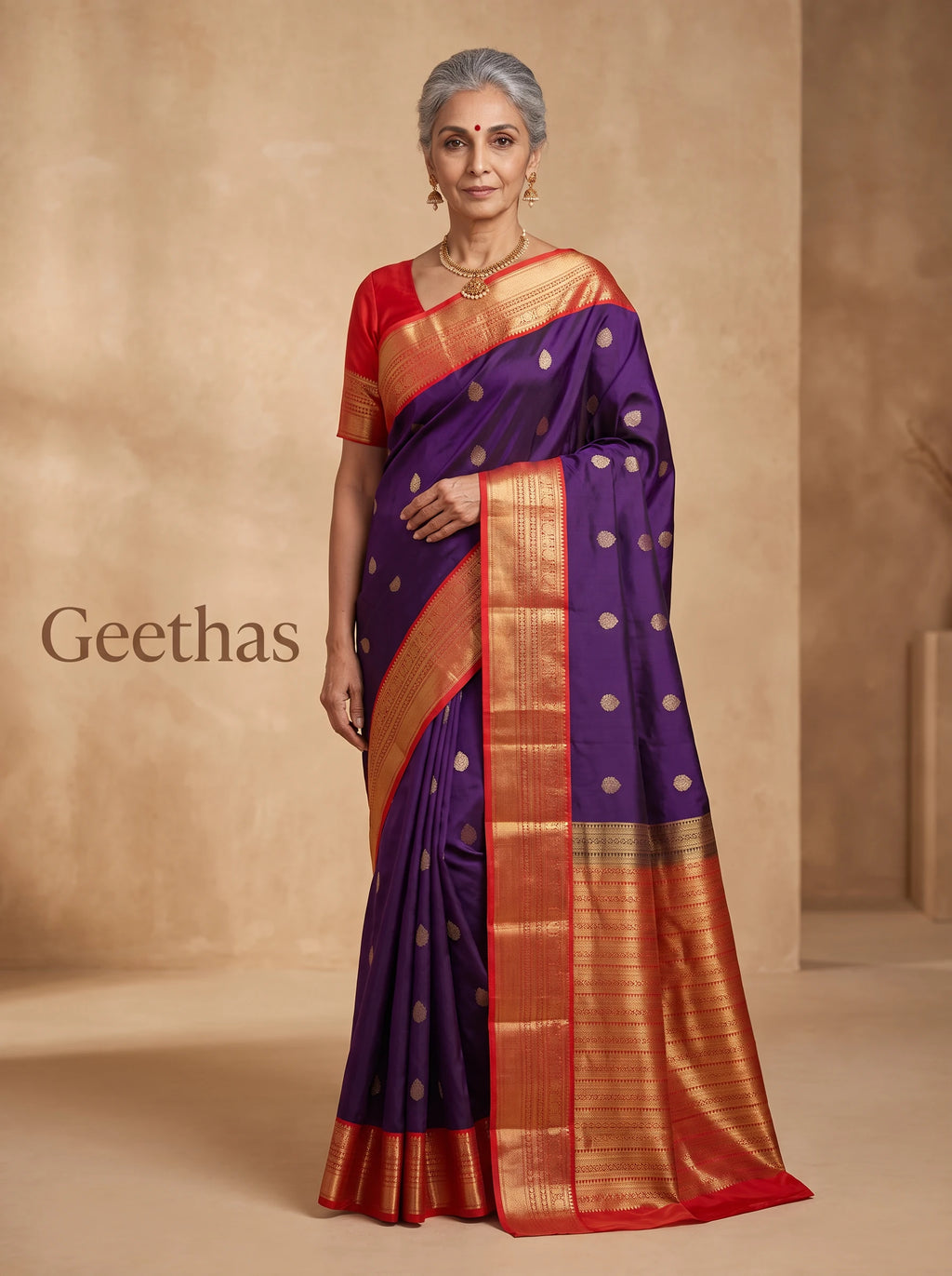 Model wearing a deep blue soft silk saree with gold-toned woven motifs and a red-edged zari border.
