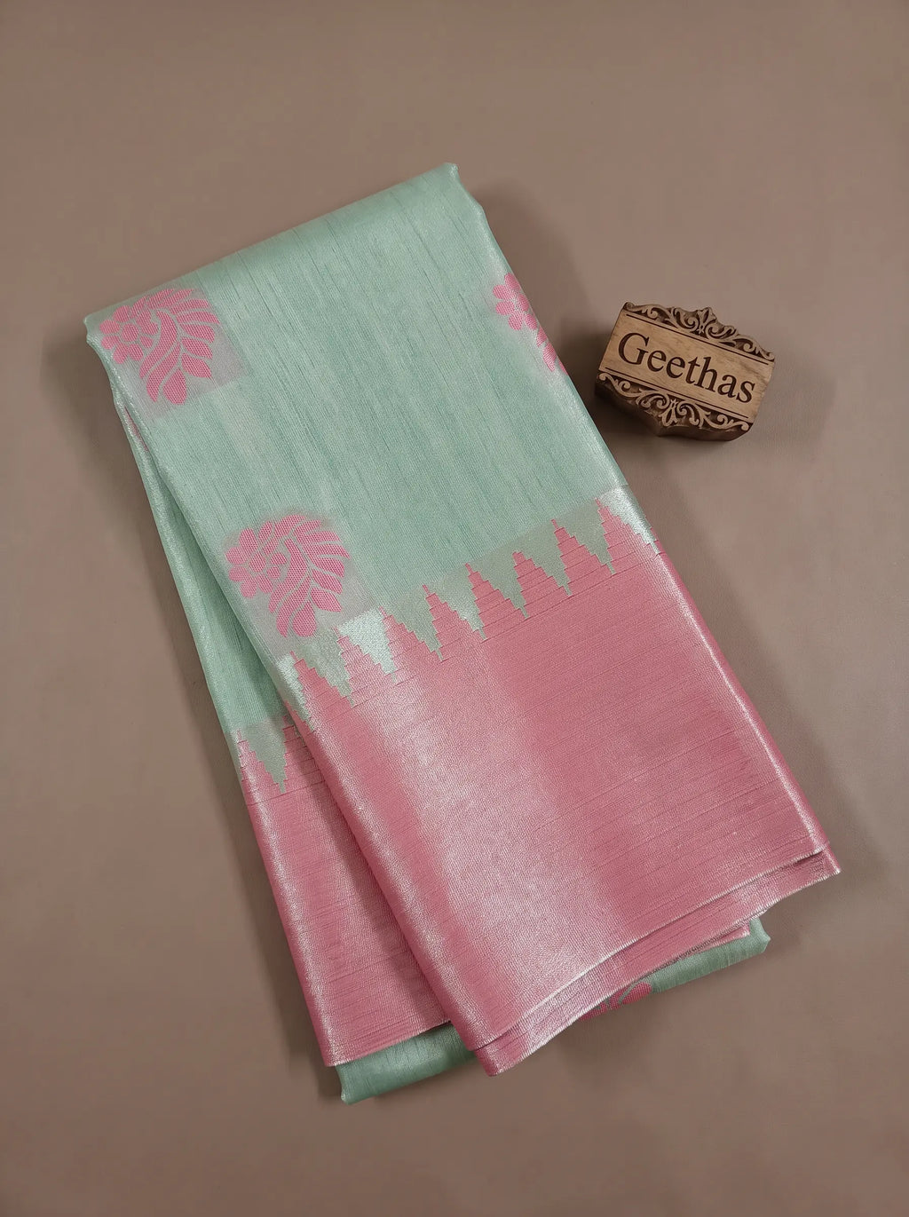 Folded mint green tissue soft silk saree with pink border and paisley-inspired woven motifs
