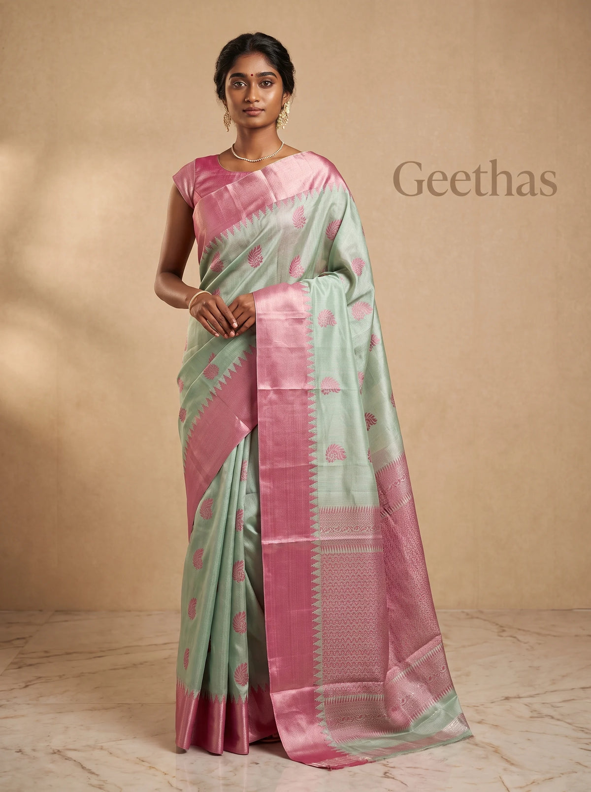 Model wearing mint green tissue soft silk saree with pink paisley-inspired motifs and contrasting pink pallu